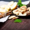 A bowl of apples and cinnamon sticks on a table.