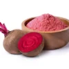 A bowl of beet powder next to two beets.