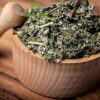A wooden bowl filled with leafy greens on top of a table.